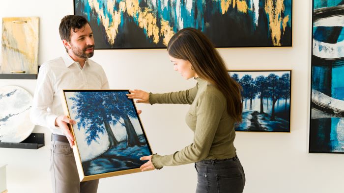 Art curators holding a painting in a gallery