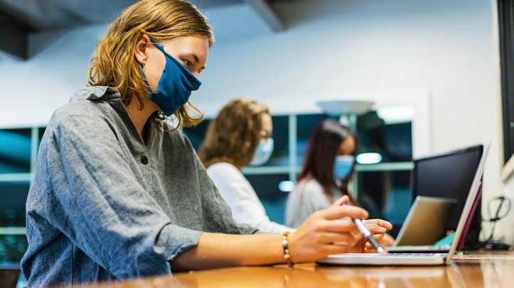 Student works from laptop with mask